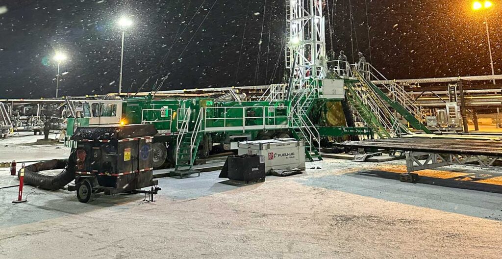 Heavy-duty oilfield drilling rig equipment at night, snow, cold weather, industrial setup, REIC Specialty Rentals.