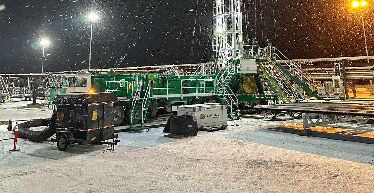 Heavy-duty oilfield drilling rig equipment at night, snow, cold weather, industrial setup, REIC Specialty Rentals.